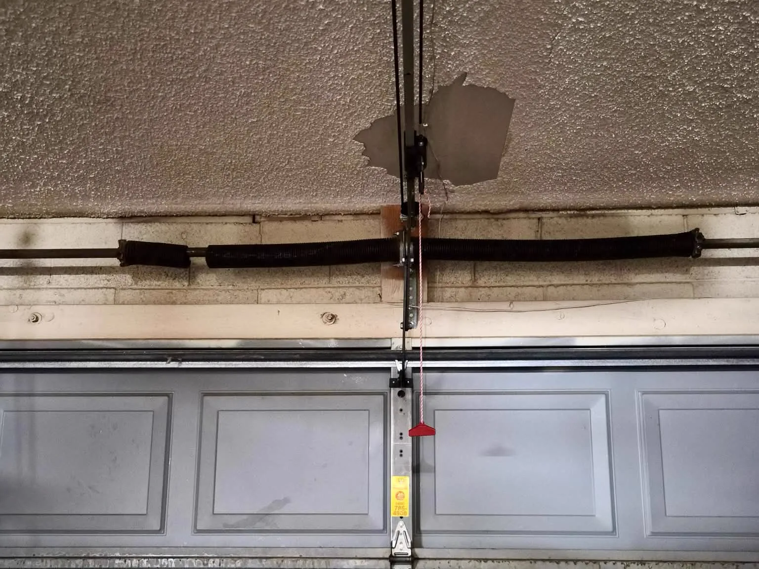 Before: broken garage door torsion spring with a visible gap in the coils above the door in Mesa