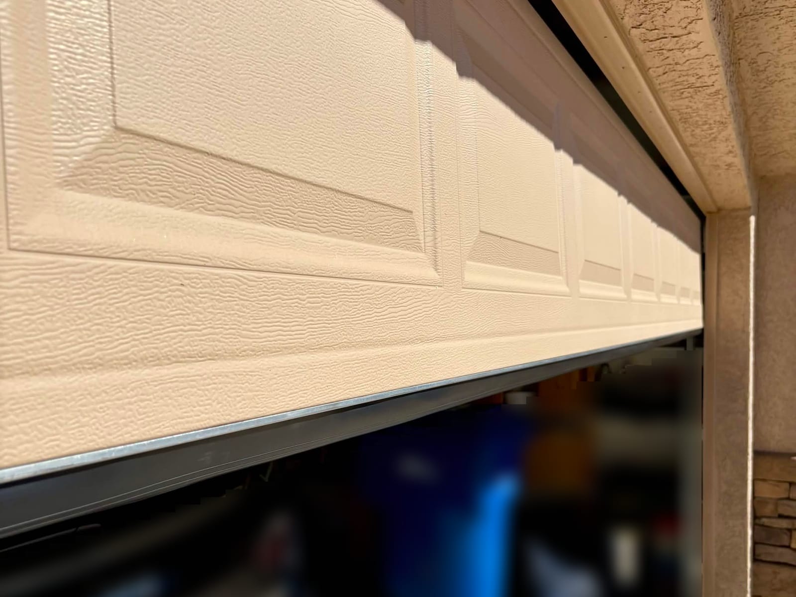After: new aluminum universal retainer and bottom seal along the lower edge of a garage door, seen from the driveway in Mesa