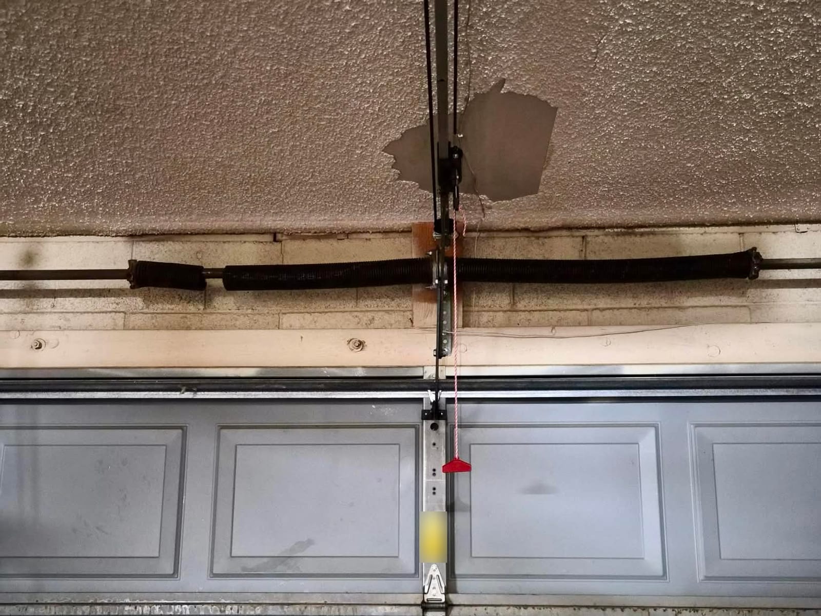 Before: broken garage door torsion spring with a visible gap in the coils above the door in Mesa