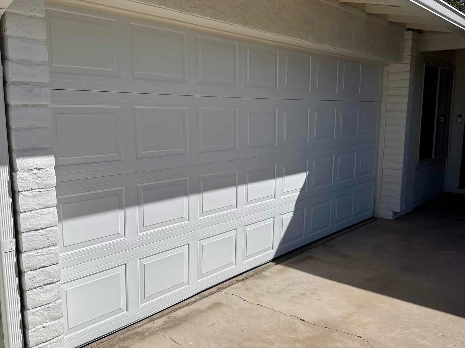 After: new heavier gauge steel raised-panel garage door, closed, in the same opening in Mesa