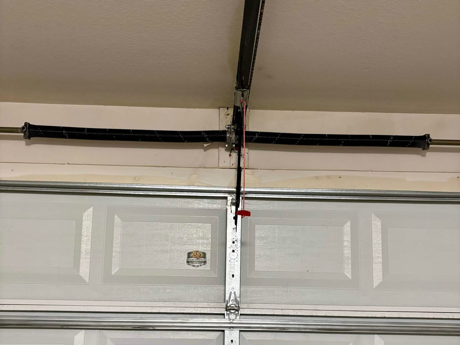 After: two new torsion springs on the shaft, one on each side of the center bearing plate, above a garage door in Gilbert