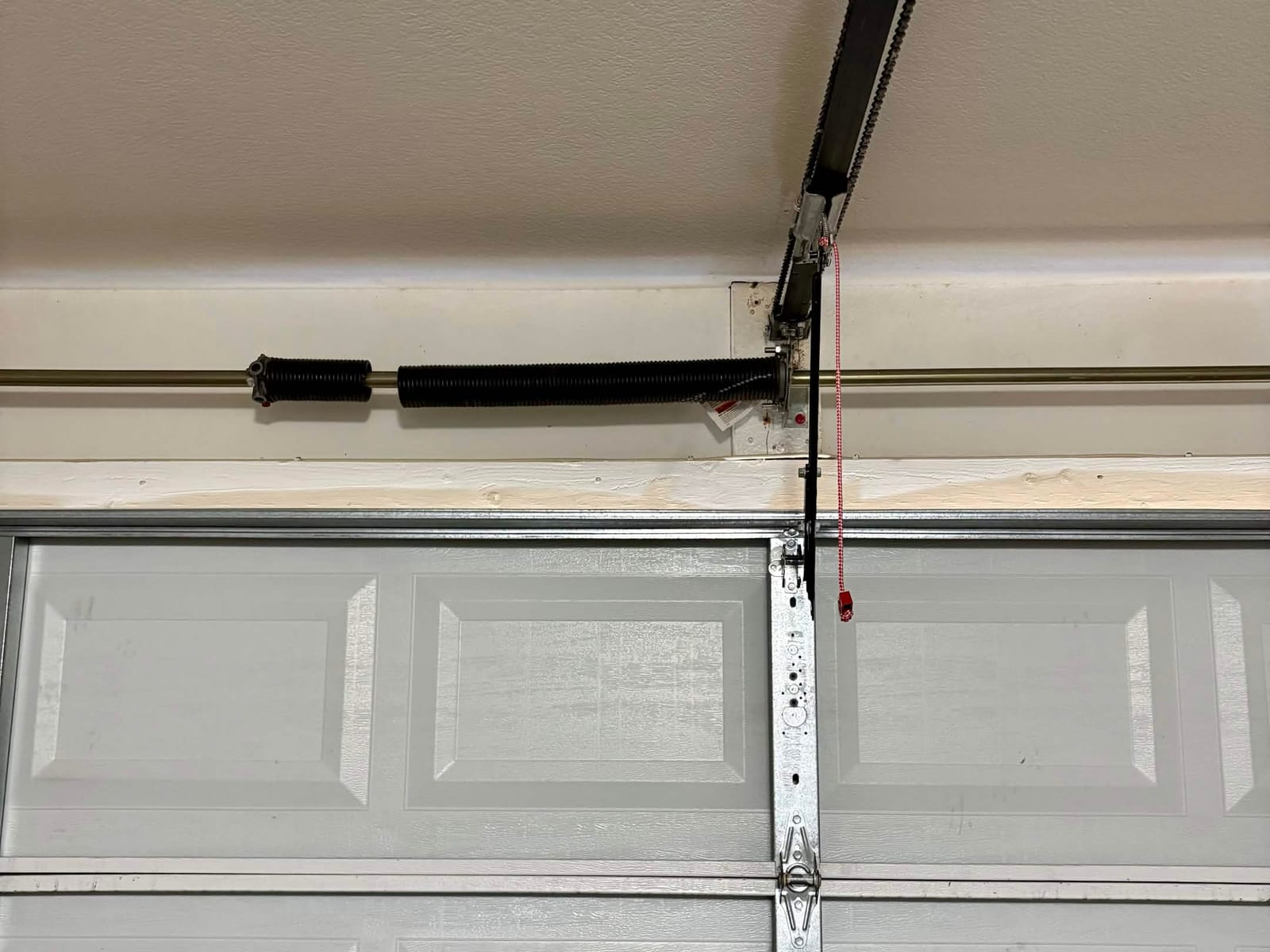 Before: single broken torsion spring with a visible gap in the coils above a double-wide garage door in Gilbert
