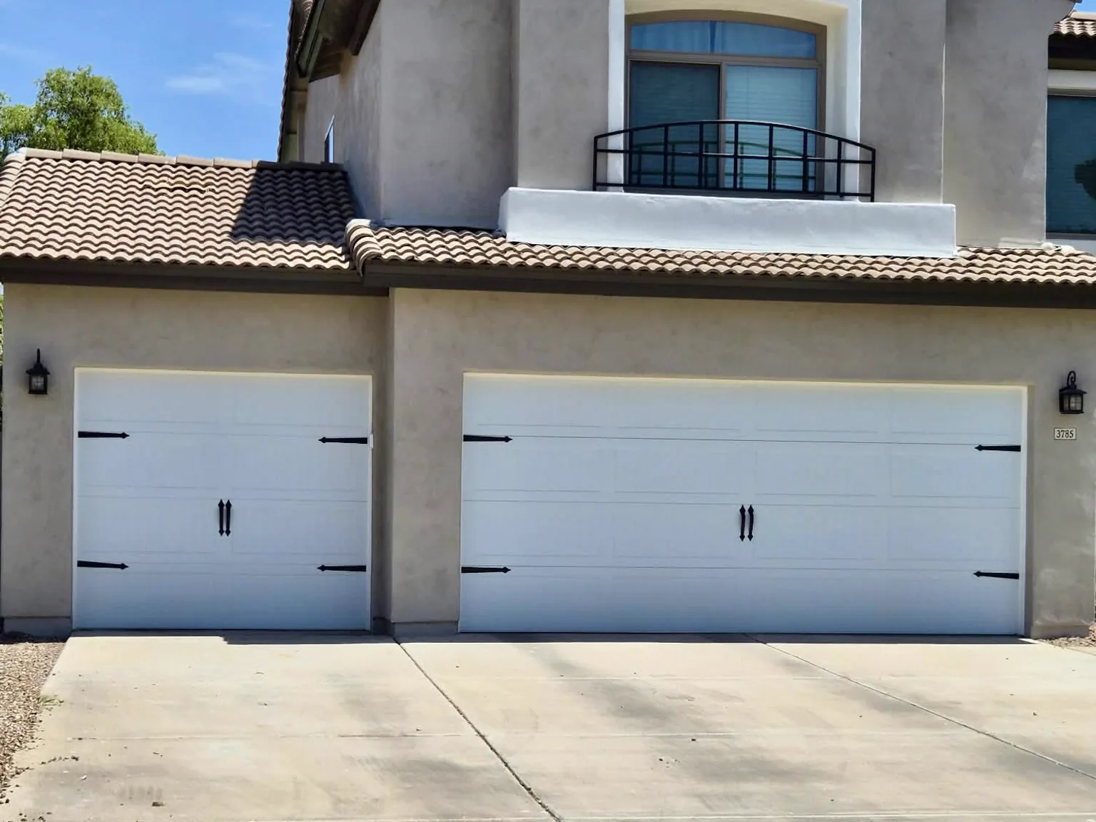 After: white insulated carriage-style garage doors with black decorative hardware in Gilbert