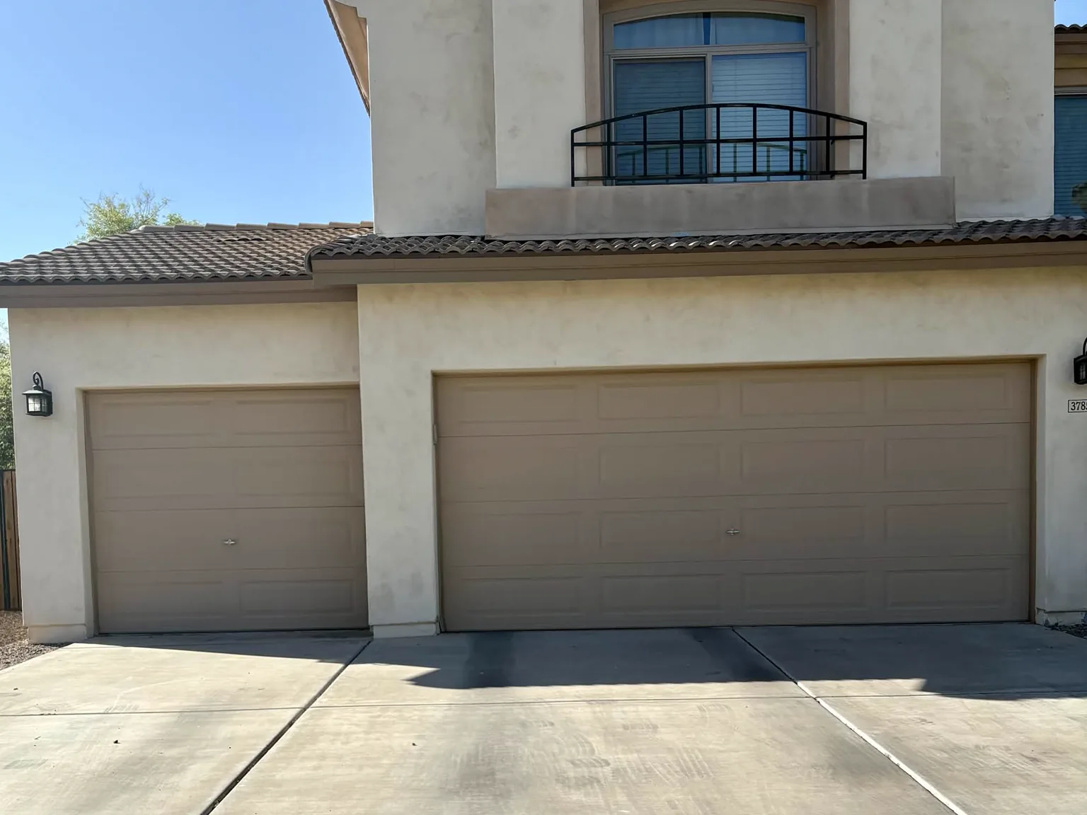 Before: two tan builder-grade garage doors on a three-car garage in Gilbert