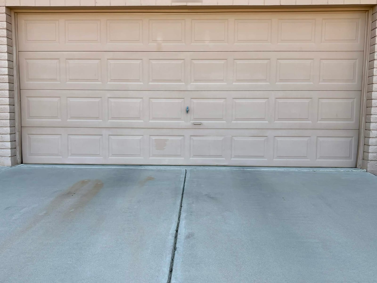 Faded tan west-facing short-panel garage door before replacement in Apache Junction, AZ