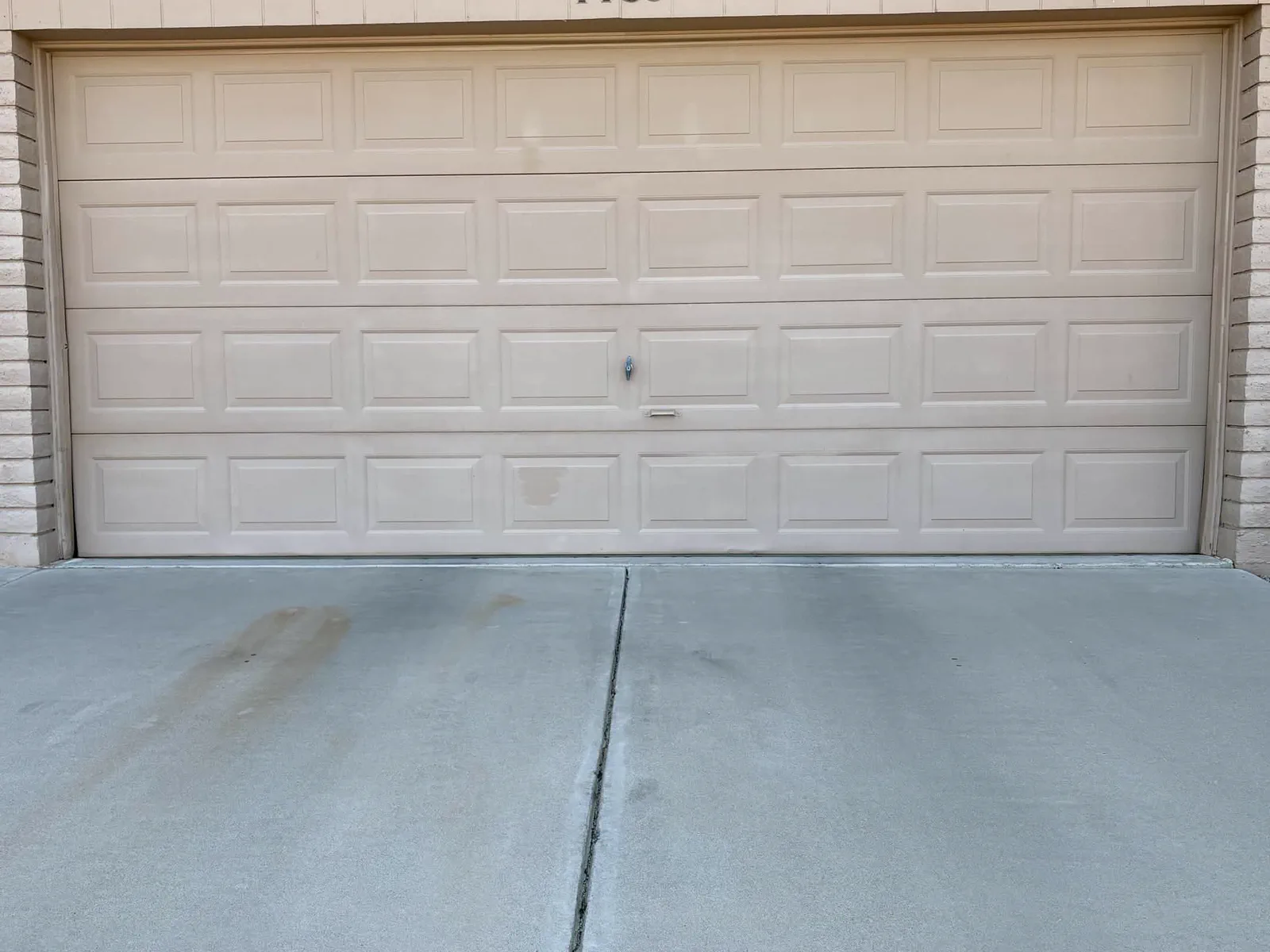 Faded tan west-facing short-panel garage door before replacement in Apache Junction, AZ