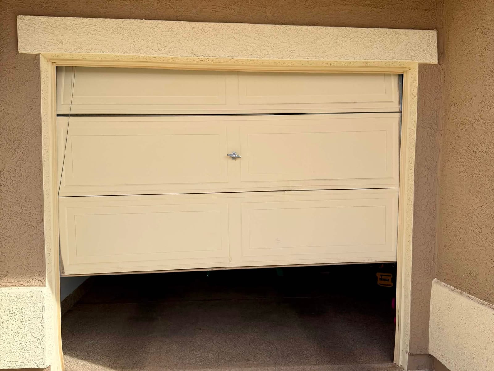 Before: single-car garage door off its track, hanging crooked and stuck partway open in Mesa