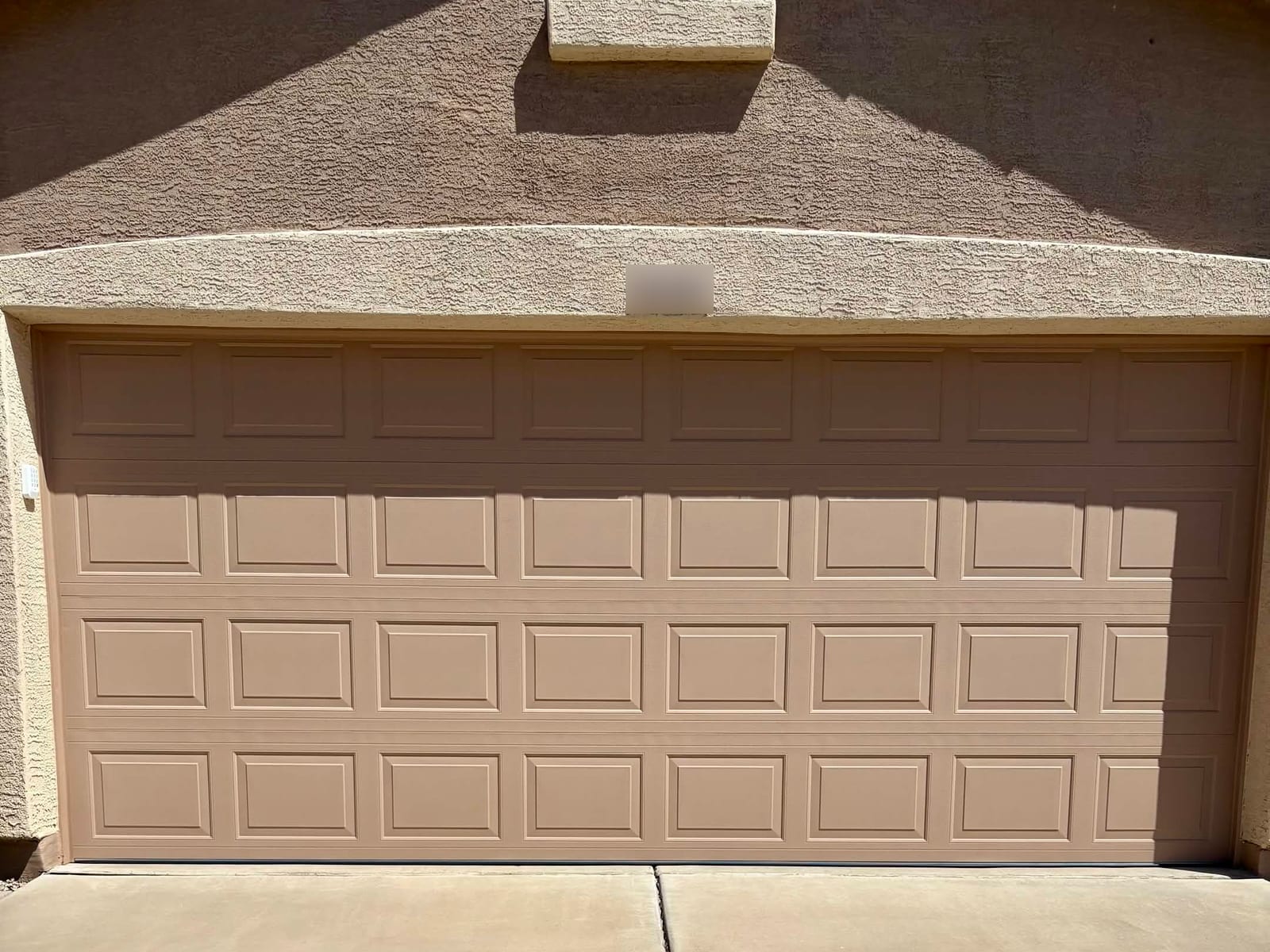 After: new insulated tan raised-panel double garage door that matches the stucco trim in Mesa